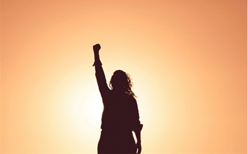 A person raising her fist in the air
Description automatically generated